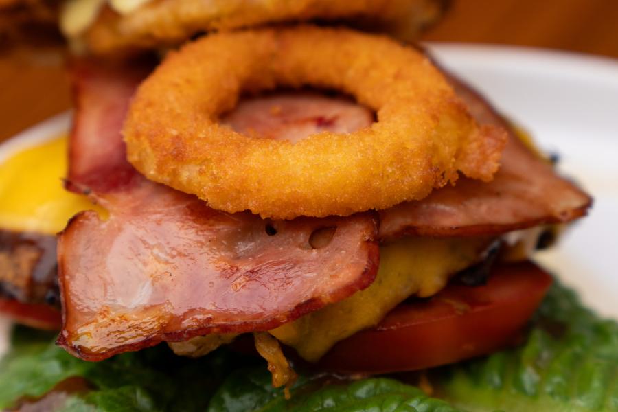 Hamburguesa tejana, jugosa carne bañanda con bbq, con tocino y dos aros crujientes de cebolla, vegetales frescos y papas fritas.