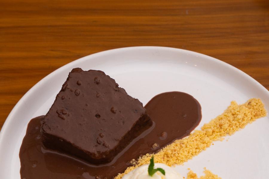 torta mojada de chocolate acompañada con helado de vainilla y galleta